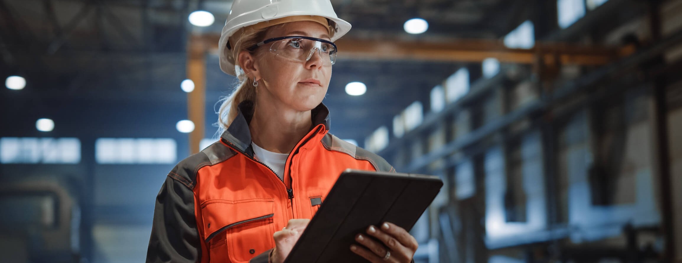 Professional Heavy Industry Engineer/Worker Wearing Safety Uniform and Hard Hat Uses Tablet Computer
