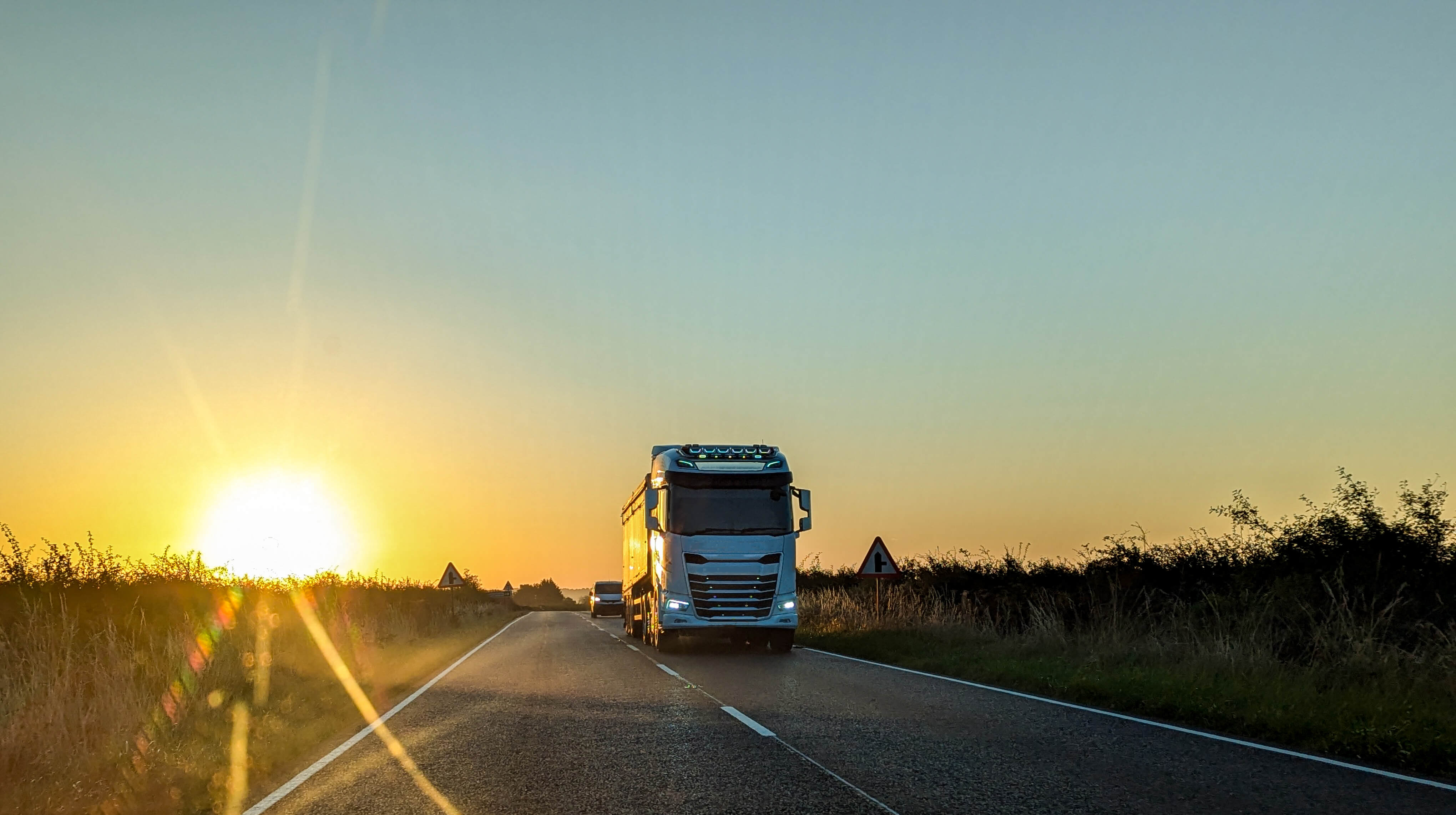 A Heavy Goods Lorry Coming Towards Another Vehicle With A Beautiful Sunset In The Background